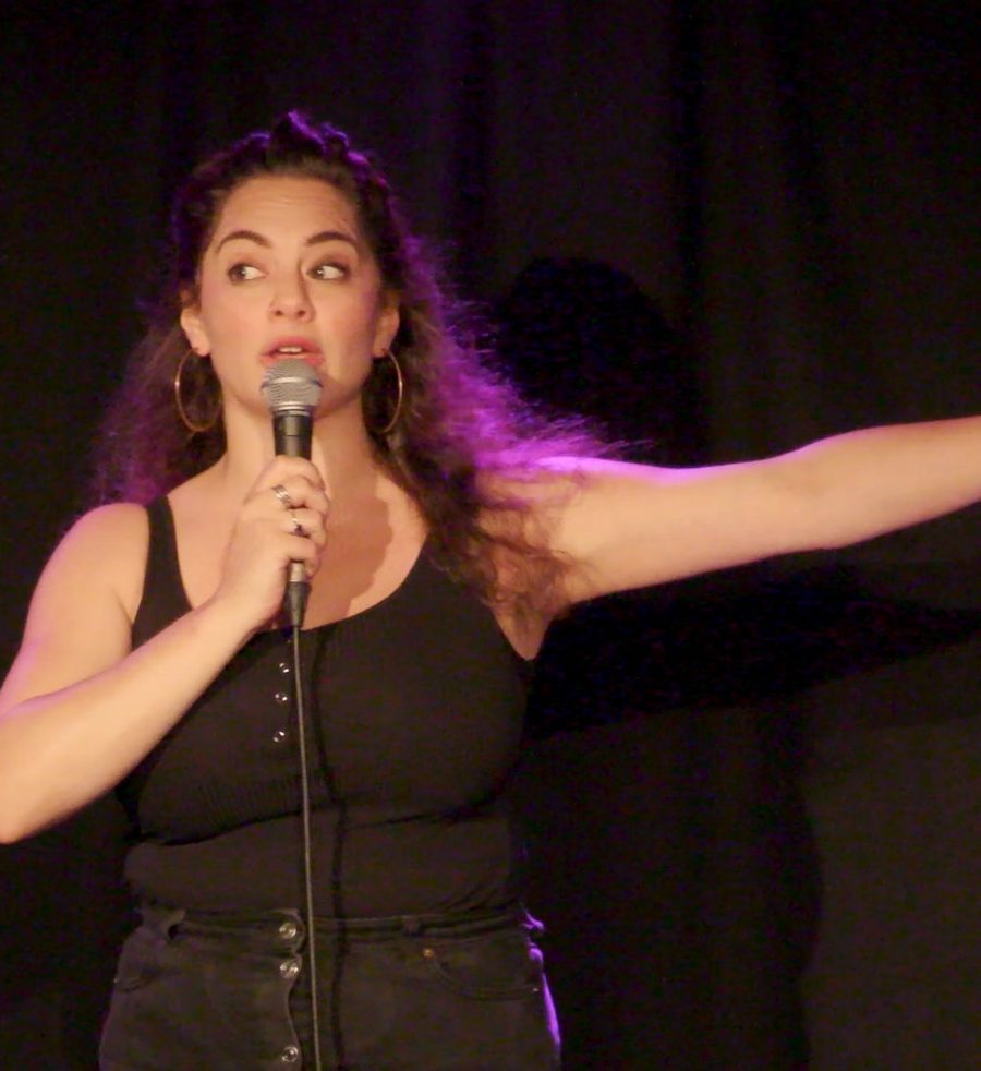 Isabelle Farah on stage with a microphone, one arm flung out to the side