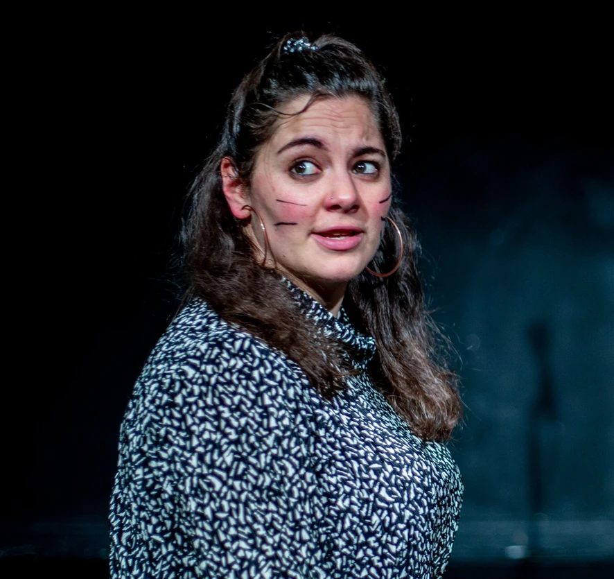 Isabelle Farah on stage, glancing sideways, with whiskers drawn on her cheeks